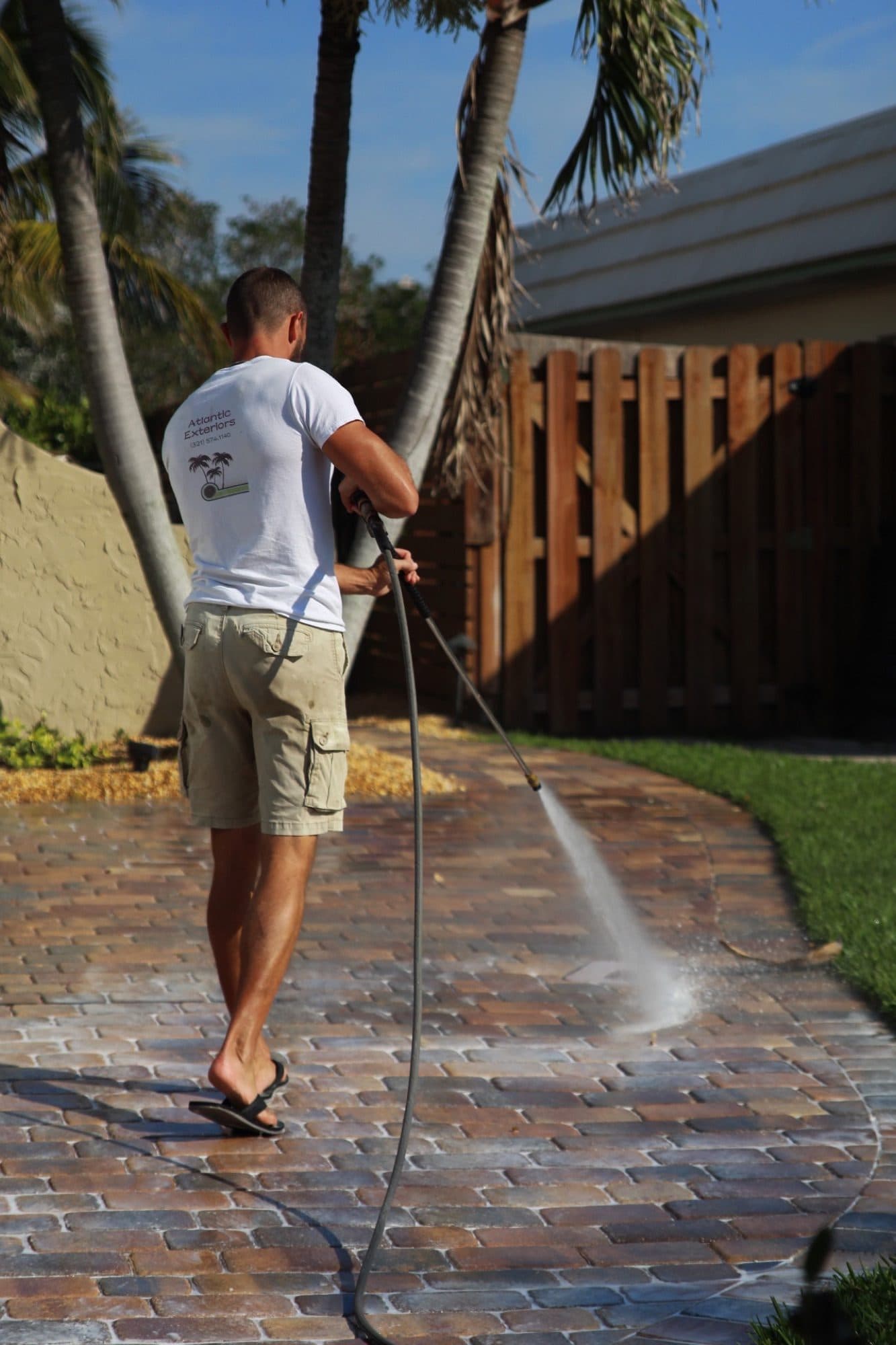 Derek pressure-washing a curved driveway — paver work by Atlantic Exteriors in Brevard County, FL