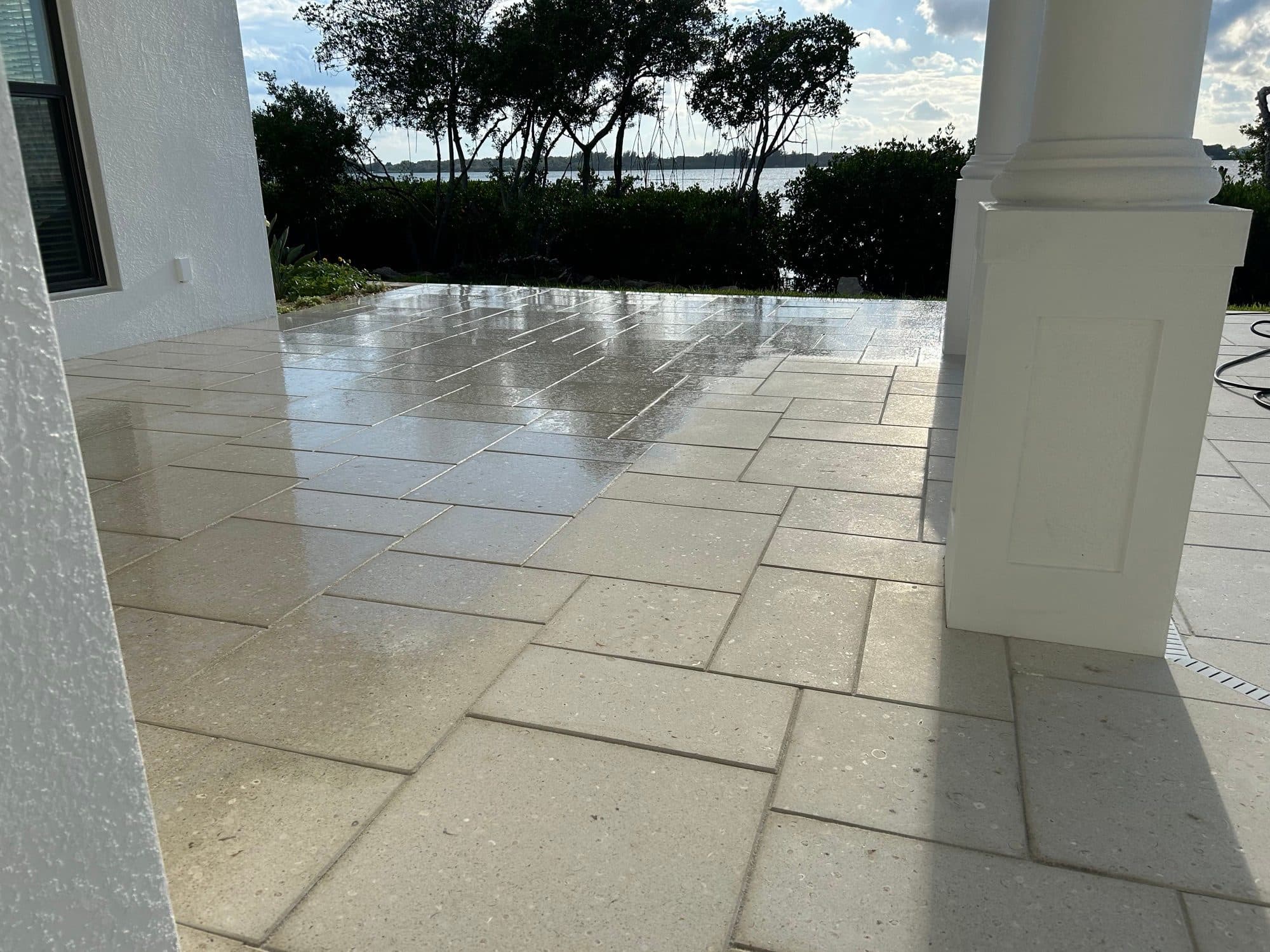 Wet travertine patio overlooking water — paver work by Atlantic Exteriors in Brevard County, FL